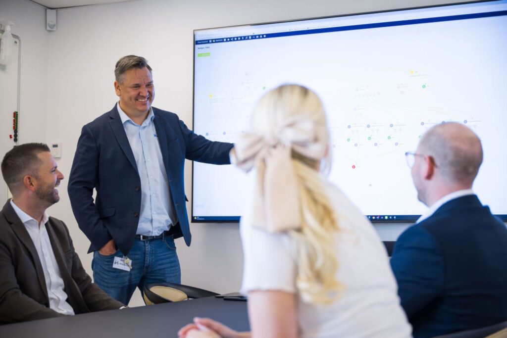 Mand præsenterer data på storskærm for kolleger i mødelokale